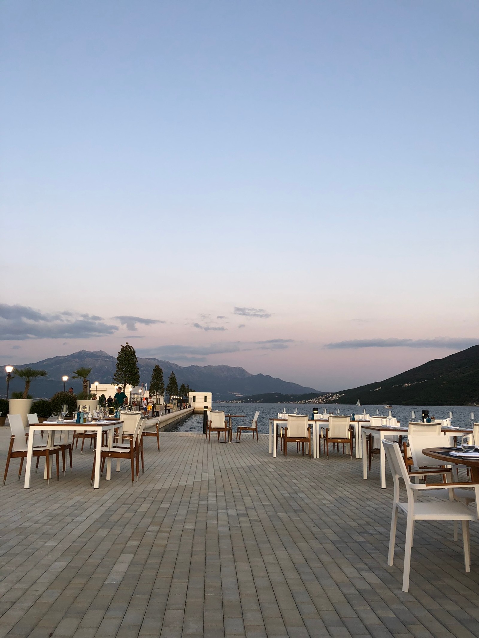 Tables and chairs on a patio overlooking a lake and mountains (sea, real estate, tourism, table, furniture)