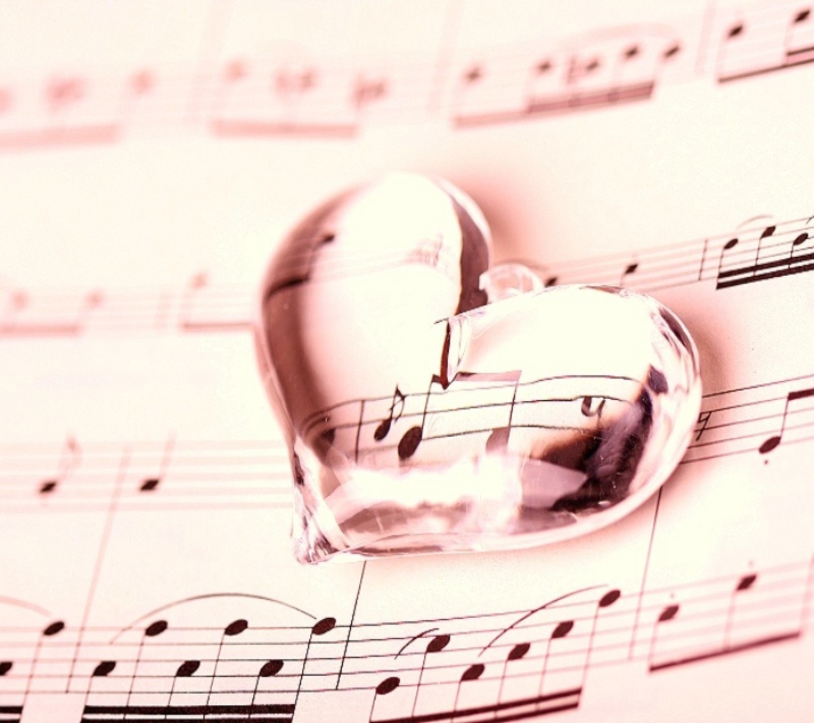 A close up of a heart shaped glass object on a sheet of music (cute, heart, love, music, romance)