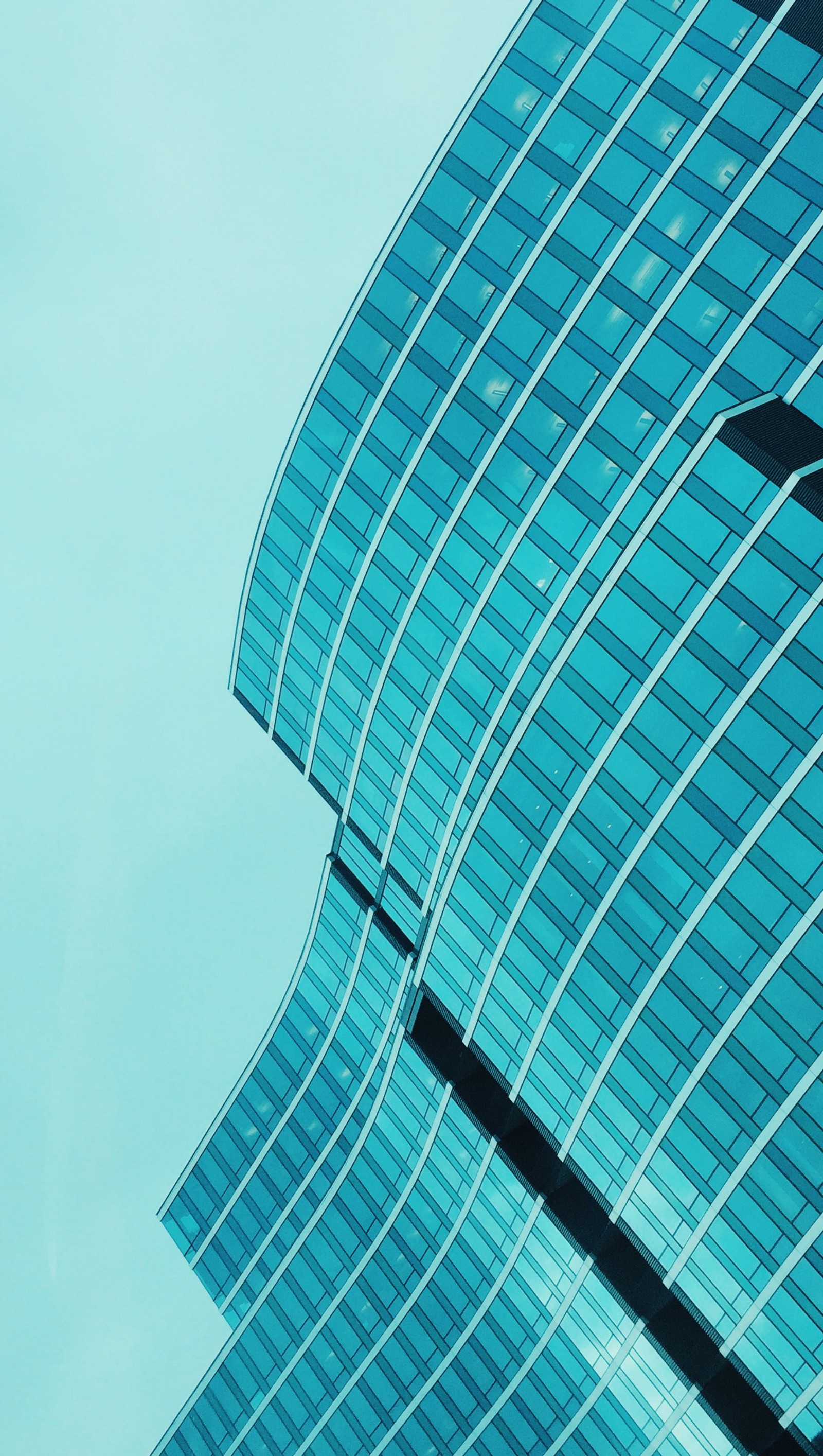 Araffle view of a plane flying in front of a building (architecture, blue, facade, geometry, glass)