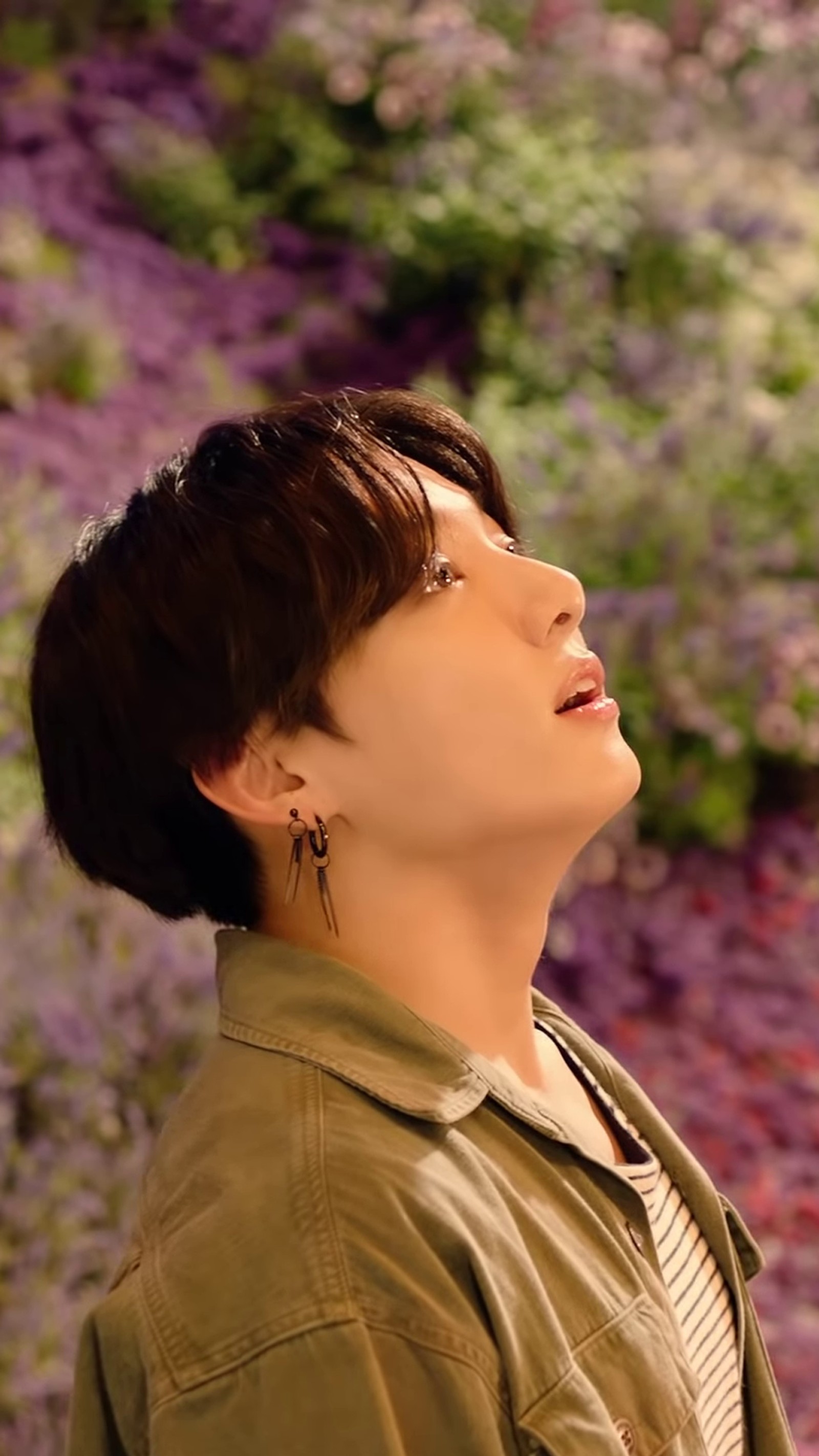 Eine nahaufnahme einer person mit einer grünen jacke auf einem blumenfeld (bangtan, bts, j hope, jhope, jimin)