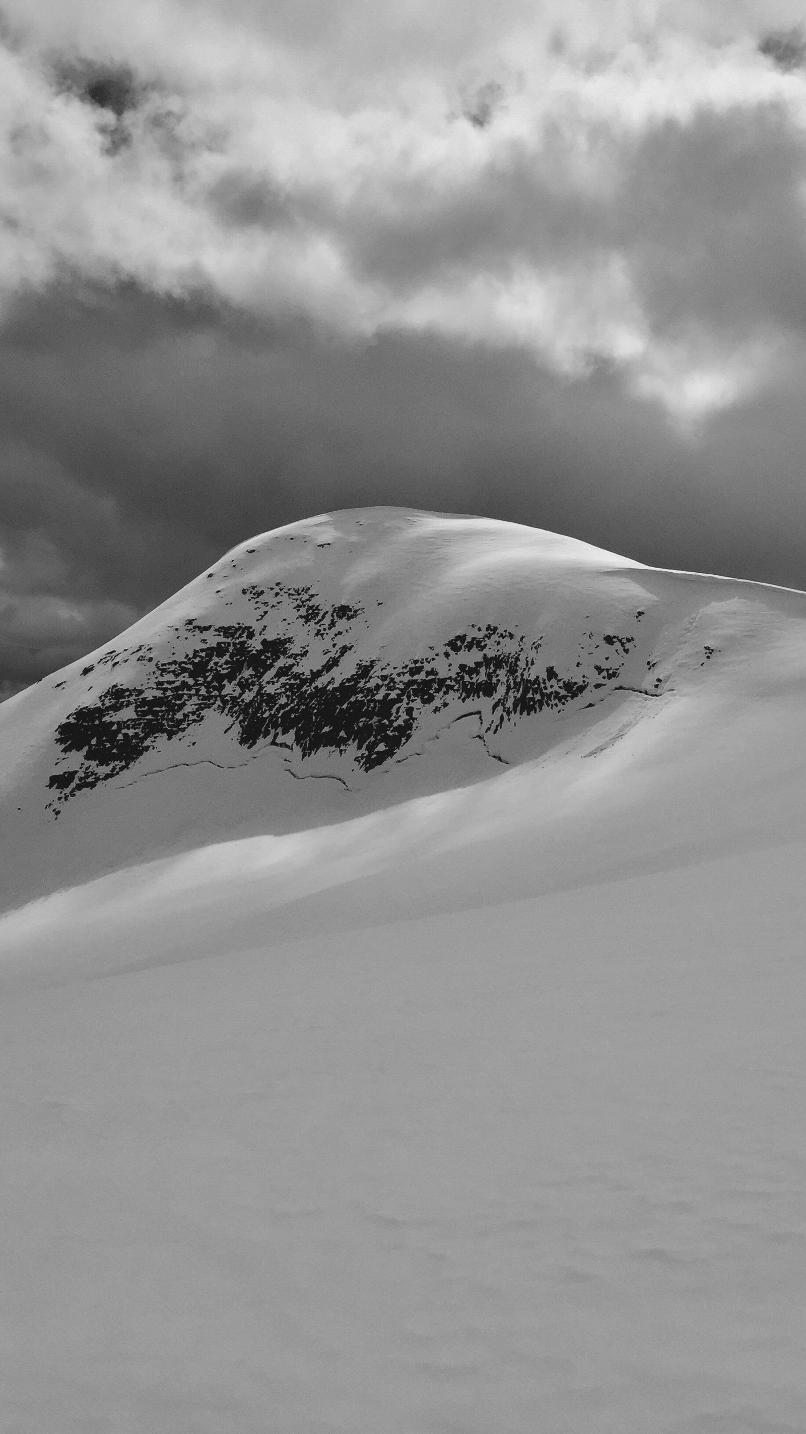 Des skieurs montent une montagne enneigée sous un ciel nuageux (montagne, nature, neige, hiver)