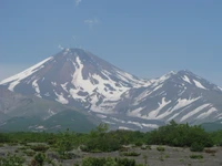 Majestueux stratovolcan entouré d'une nature luxuriante et de sommets enneigés