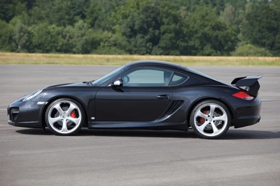 Porsche Cayman noir élégant avec des modifications Techart, mettant en valeur un design sportif et des jantes améliorées sur une piste dégagée.