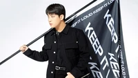 Choi Jongho do ATEEZ posa confiantemente com uma bandeira ousada, incorporando a energia do K-pop.