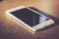 Sleek white smartphone resting on a wooden surface.