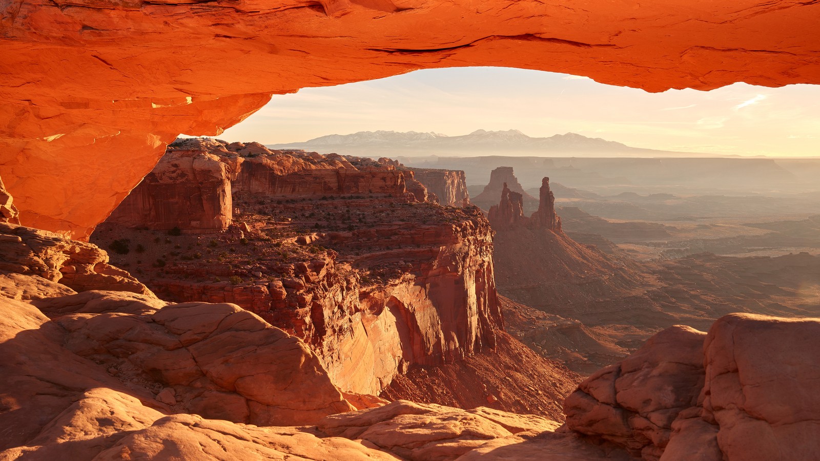 Une vue d'un canyon avec une grande arche au milieu (arc de mesa, parc national, formation, badlands, roche)