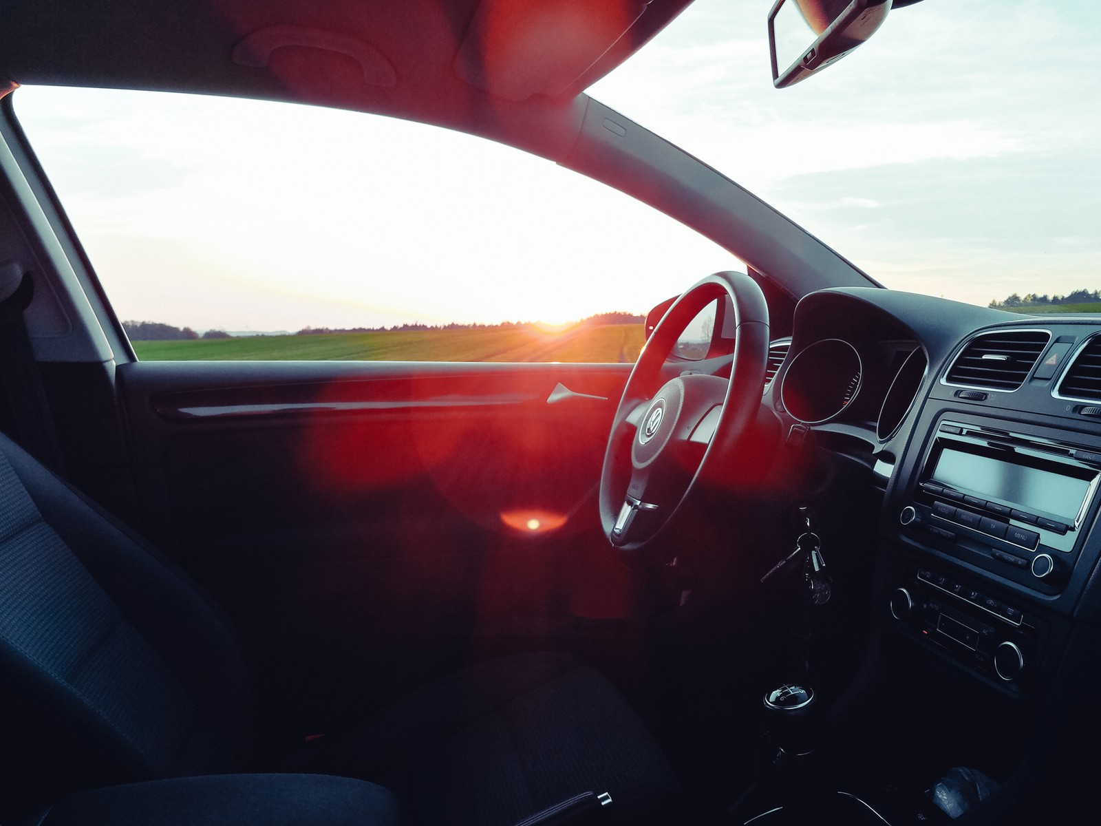 Vue arabe d'une voiture avec le soleil brillant à travers le pare-brise (volkswagen, voiture, volkswagen golf, volant, rouge)