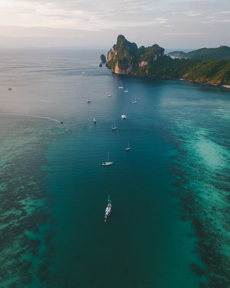 Арафедный вид группы лодок в воде у скалистого острова. (phi phi islands, вода, водные ресурсы, облако, лодка)