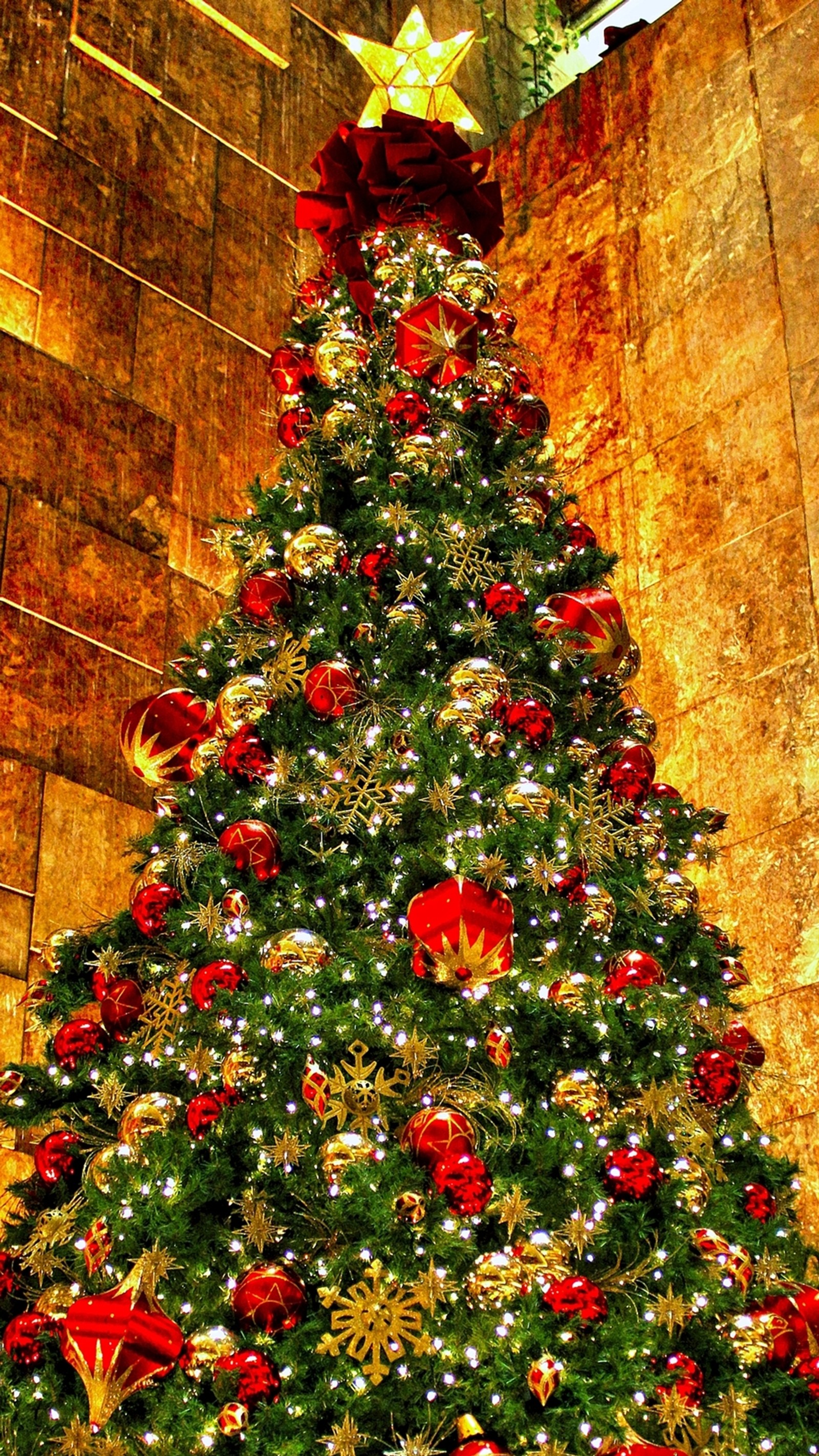 A close up of a christmas tree with decorations in a building (christmas, holiday, tree, x mas, xmas)