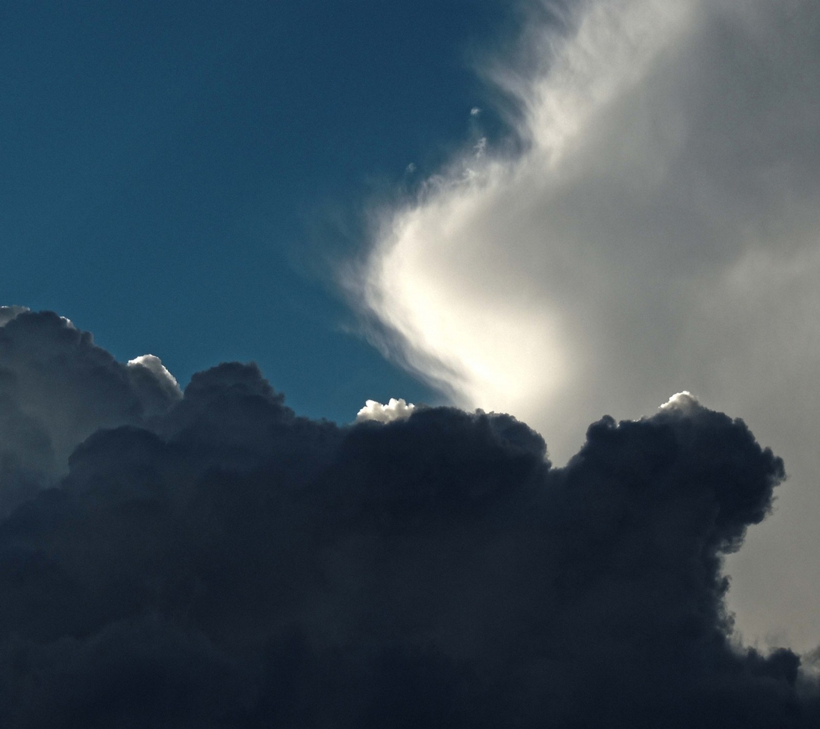 Il y a un avion volant à travers un ciel rempli de nuages (et blanc, noir)