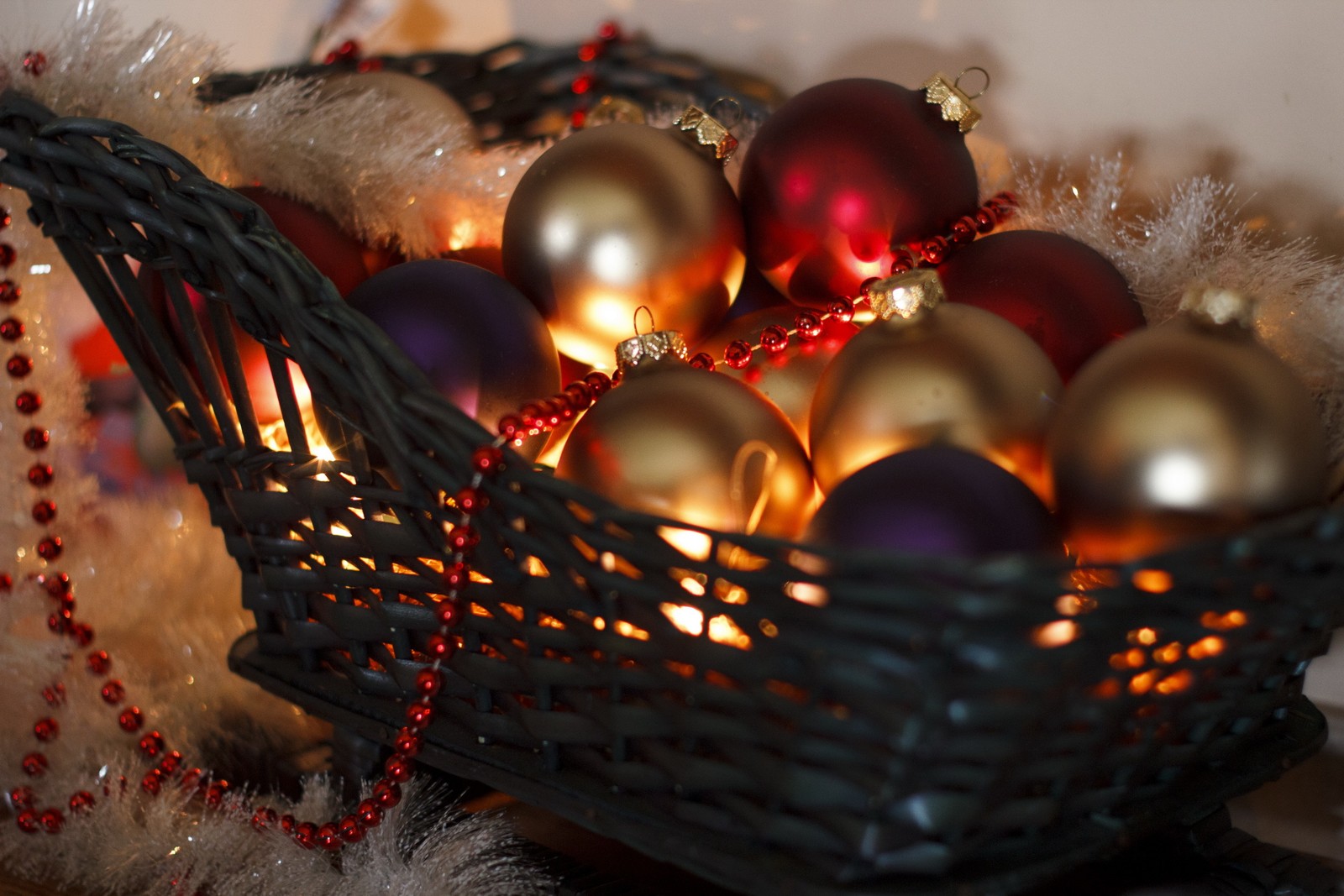 There is a basket of ornaments on a table with a candle (christmas ornament, christmas decoration, christmas, close up, decor)