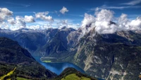 Chaîne de montagnes à couper le souffle surplombant un lac serein et des hauts plateaux luxuriants