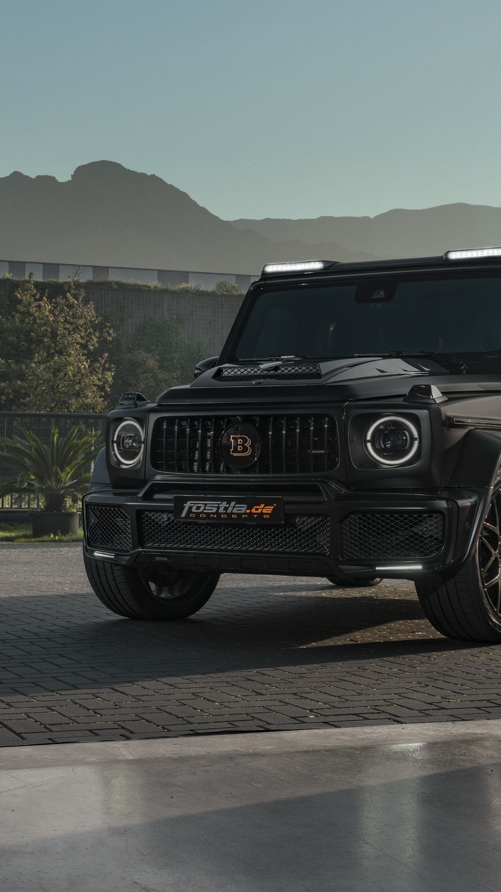 Un jeep noir garé sur une route pavée avec des montagnes en arrière-plan (mercedes, brabus, mercedes benz g class, mercedes benz, android)