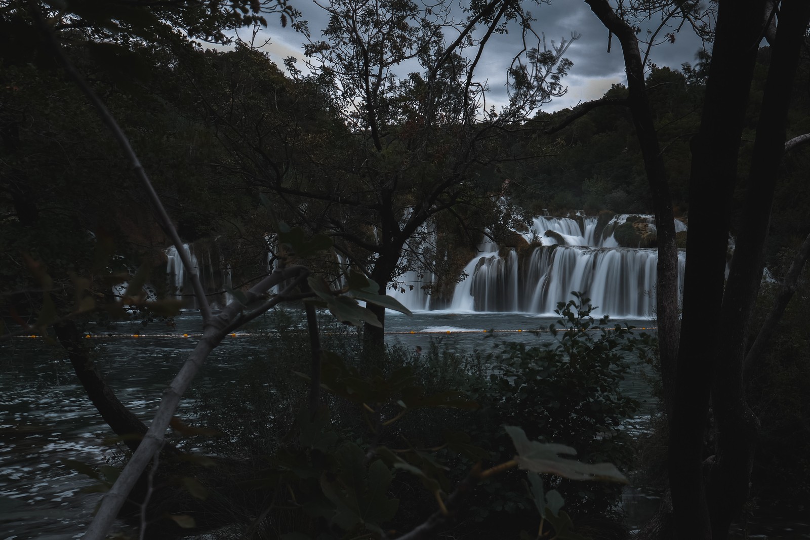 Arafed view of a waterfall with a few trees in the foreground (tree, body of water, waterfall, nature, water)