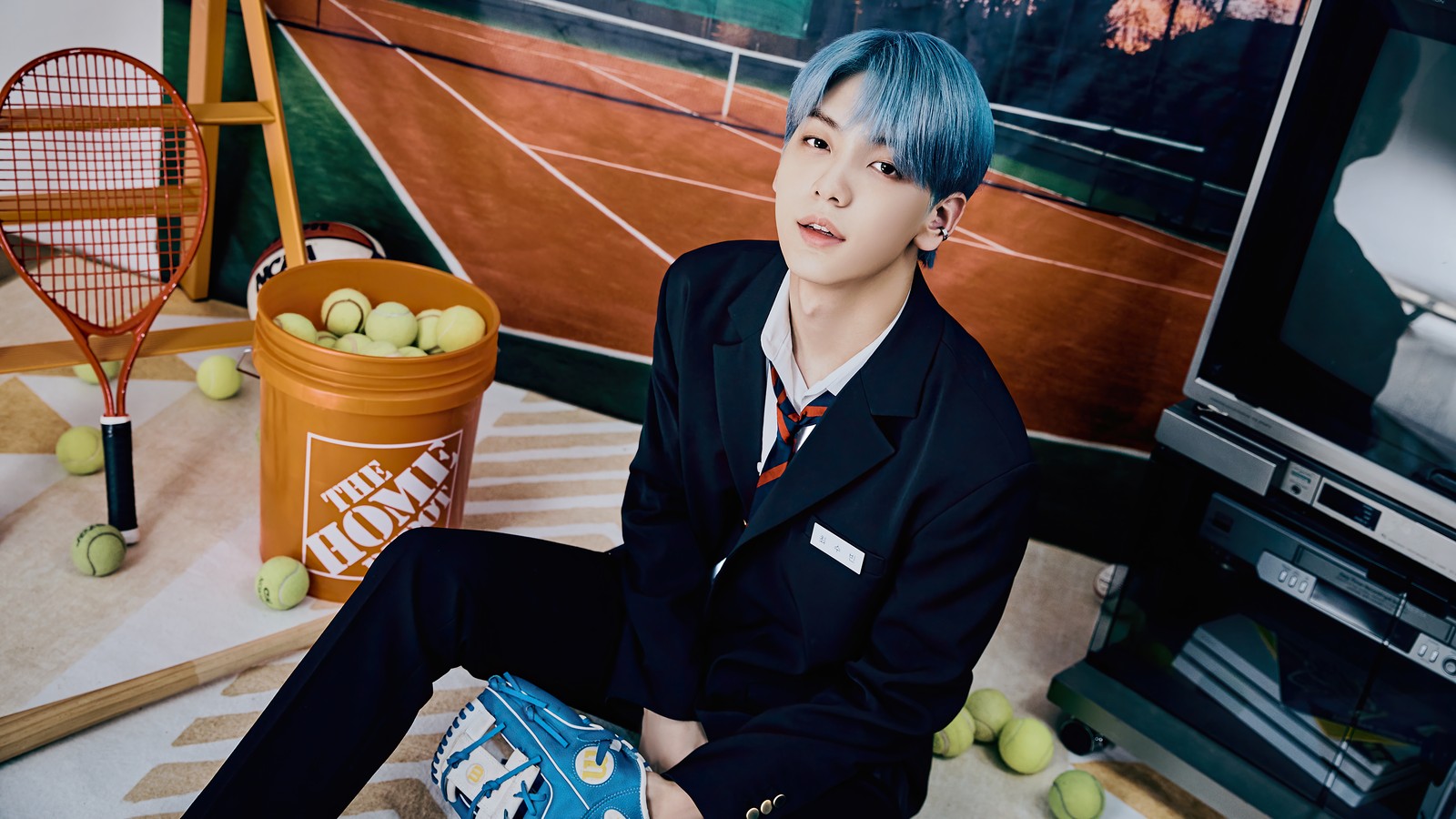 There is a man sitting on a floor with a tennis racket (txt kpop, tomorrow x together, 투모로우바이투게더, kpop, k pop)