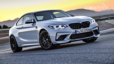 Элегантное купе BMW M2 с эффектными легкосплавными дисками на фоне золотого заката.