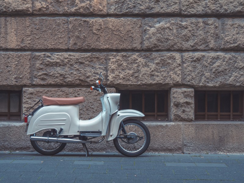 Un scooter garé sur le bord de la rue (scooter, moto, mur, voiture, piaggio)