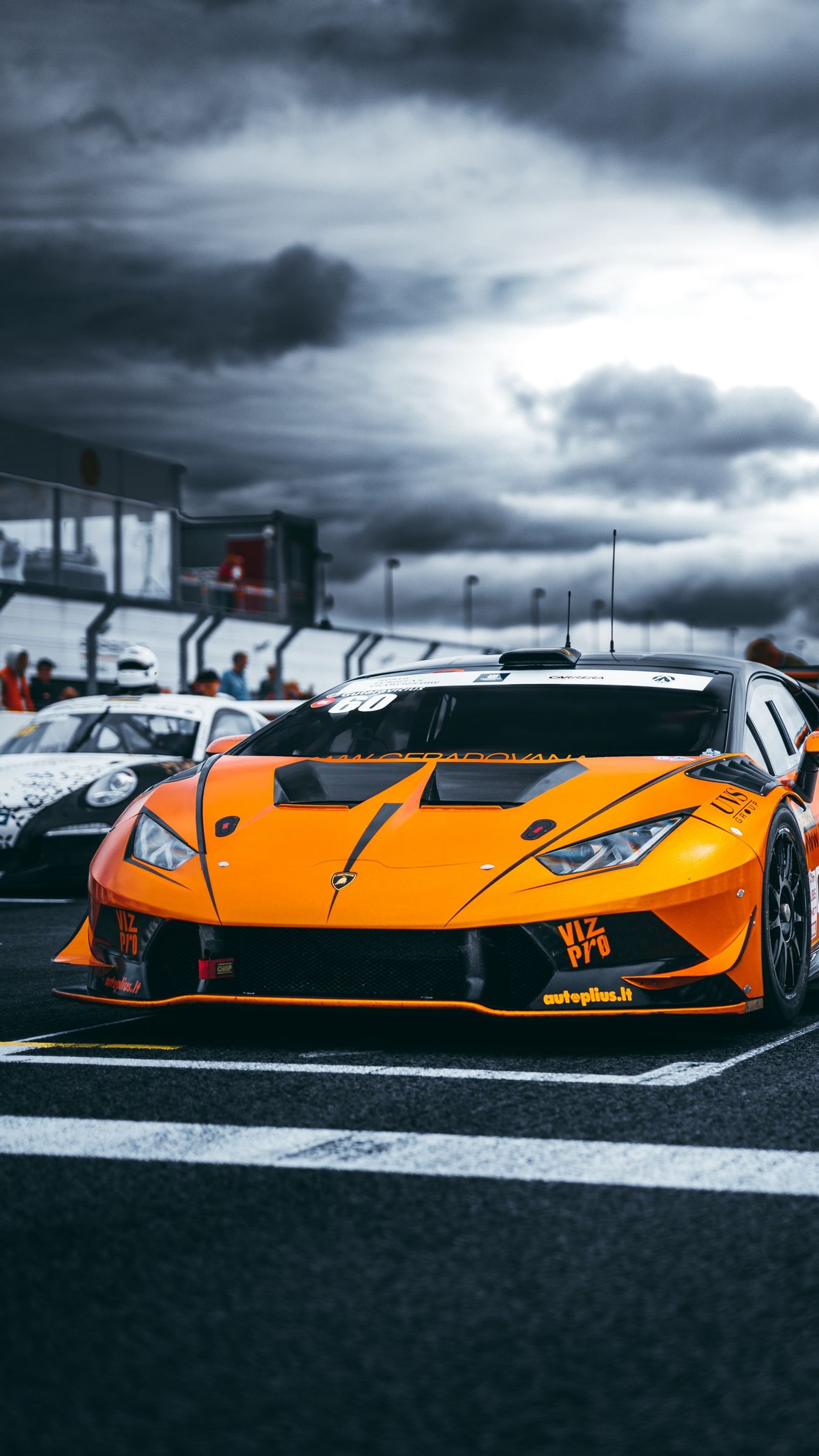 Un coche deportivo naranja árabe estacionado en una pista de carreras con otros coches (lamborghini aventador, lamborghini, coche deportivo, coches, lamborghini huracn)