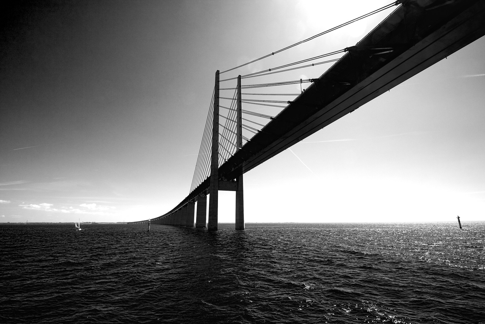 Vista aérea de un puente sobre el océano con un barco en el agua (puente, puente colgante, agua, negro, monocromo)