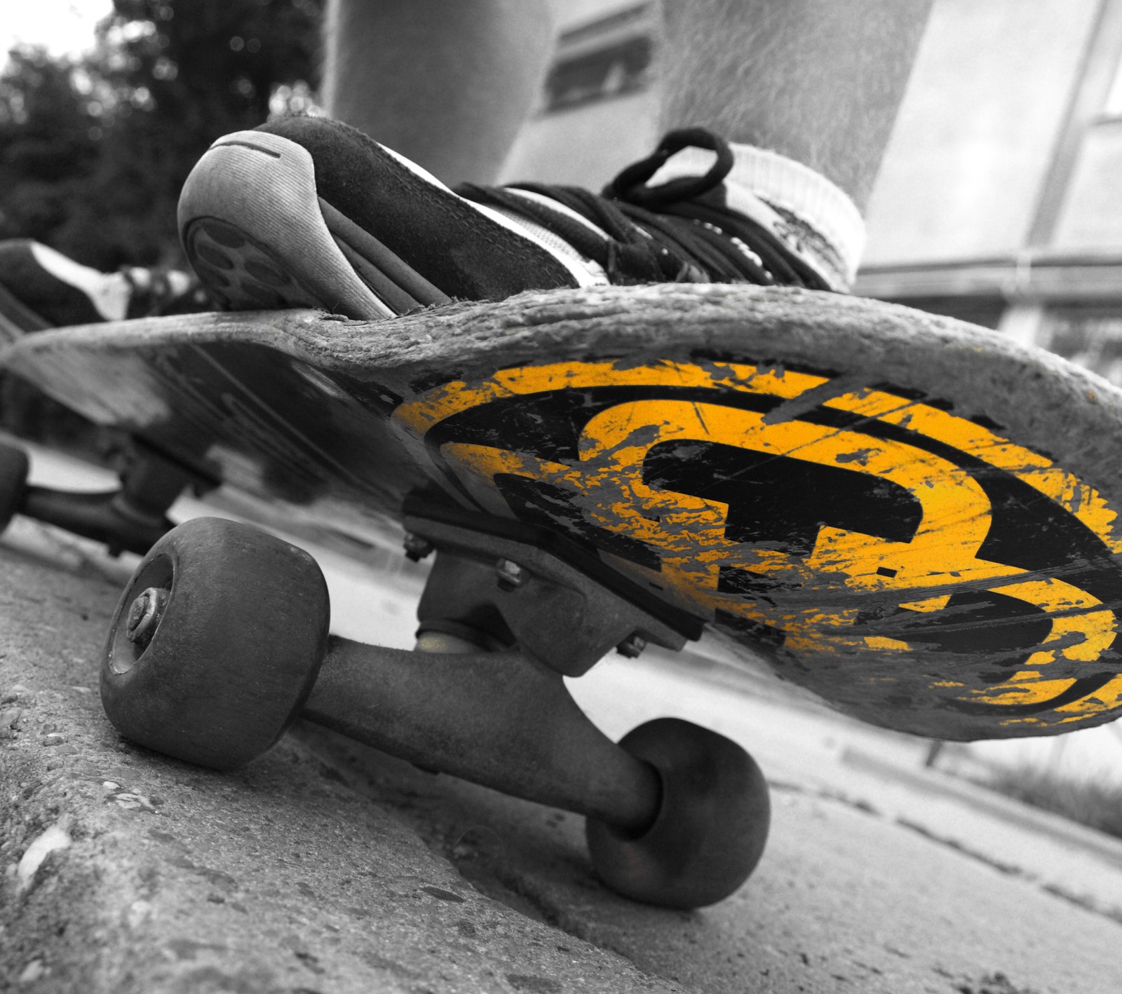 Someone is riding a skateboard on the sidewalk with their feet on it (grind, orange, pavement, shoes, skateboard)