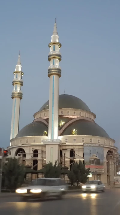 Mosquée moderne avec des minarets distincts, illuminée au crépuscule.