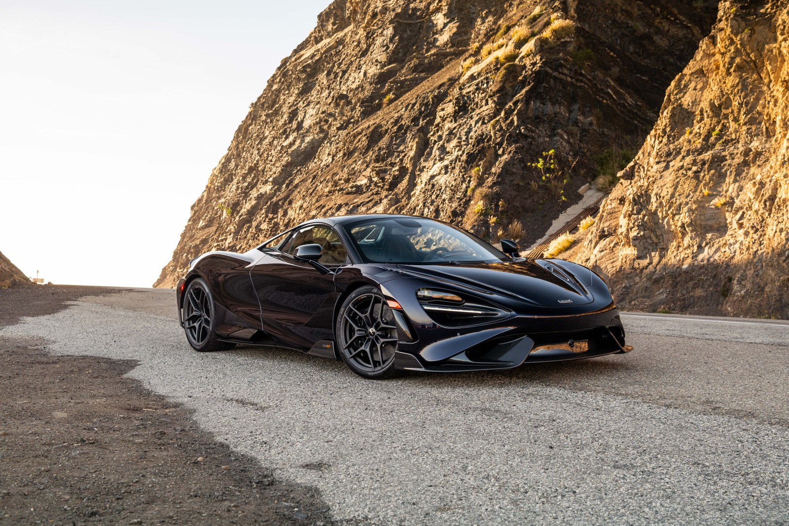 Une mclaren noire roulant sur une route de montagne (mclaren 765lt spider, 8k, 2022, 5k, voitures)