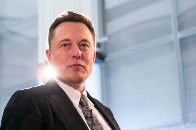 Elon Musk in einem Anzug, der Selbstbewusstsein und Charisma ausstrahlt, während einer Geschäftveranstaltung.