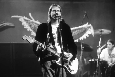 Kurt Cobain se apresentando ao vivo com um violão, incorporando a essência da música grunge contra um fundo de asas angelicais.