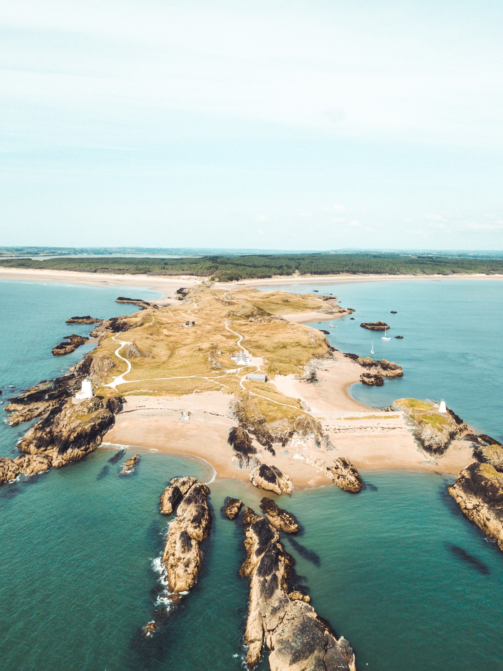 Vista aérea de uma praia com uma costa arenosa e um corpo de água (ilhéu, península, cabo, promontório, reino unido)