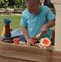 Niño participando en jardinería con macetas en el área de juegos de la casa de campo