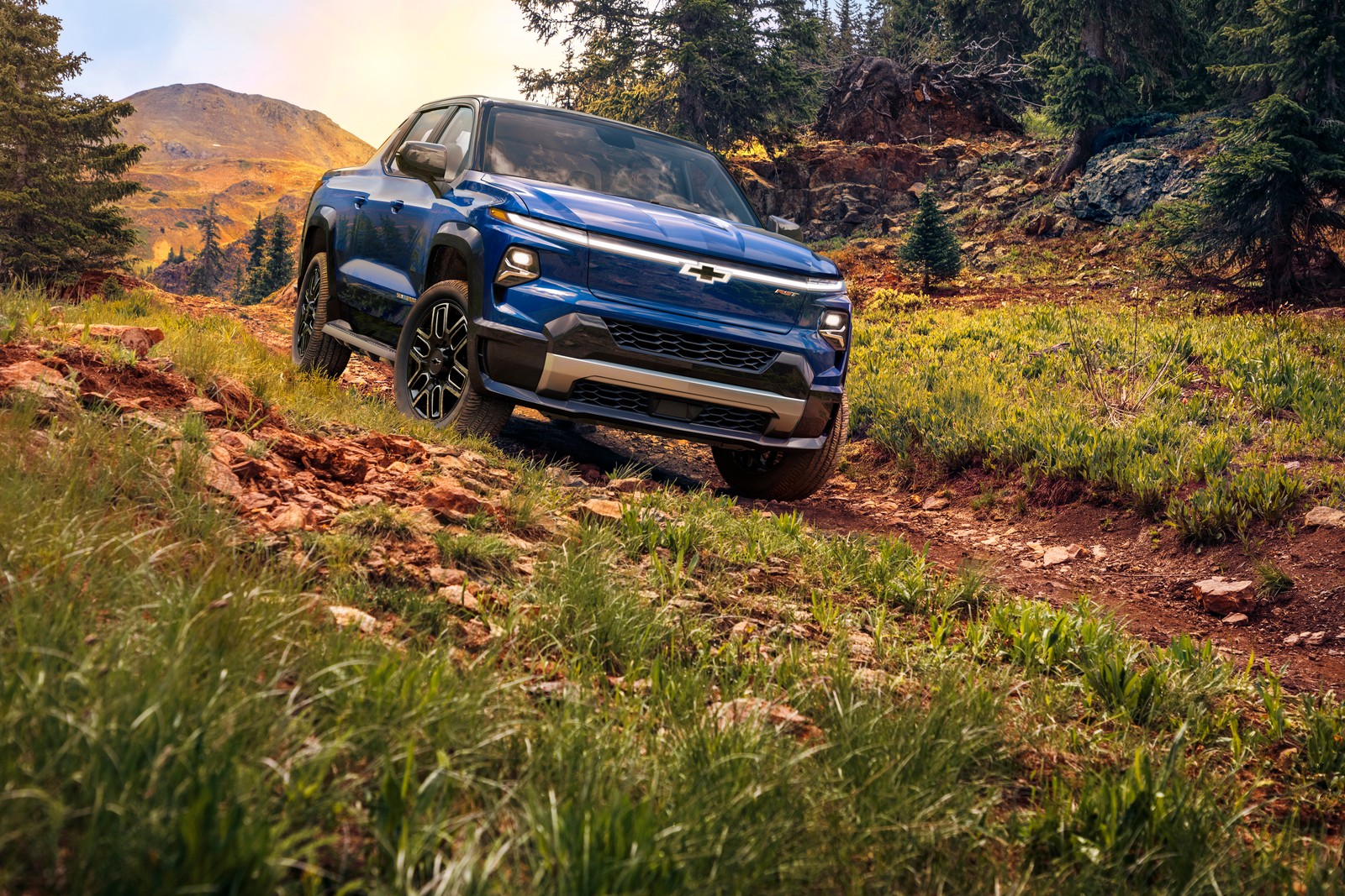 Una camioneta chevrolet colorado azul conduciendo por un camino de tierra (chevrolet silverado ev, camiones todoterreno, camiones eléctricos, concepto ev, 2024)