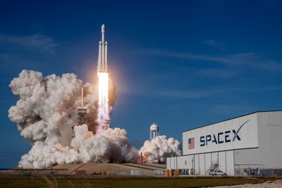 Start der SpaceX Falcon Heavy-Rakete gegen einen klaren blauen Himmel