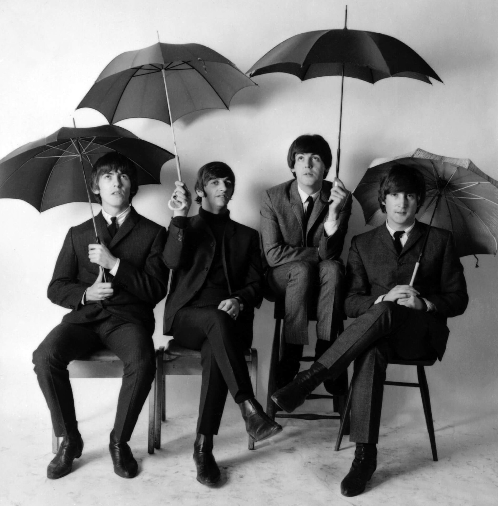 Foto en blanco y negro de un grupo de personas sentadas bajo paraguas (john lennon, the beatles, foto instantánea, monocromo, drama)