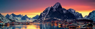 Schneebedeckte Berge spiegeln sich im ruhigen Wasser bei Sonnenaufgang und erleuchten die winterliche Wildnis von Lofoten.