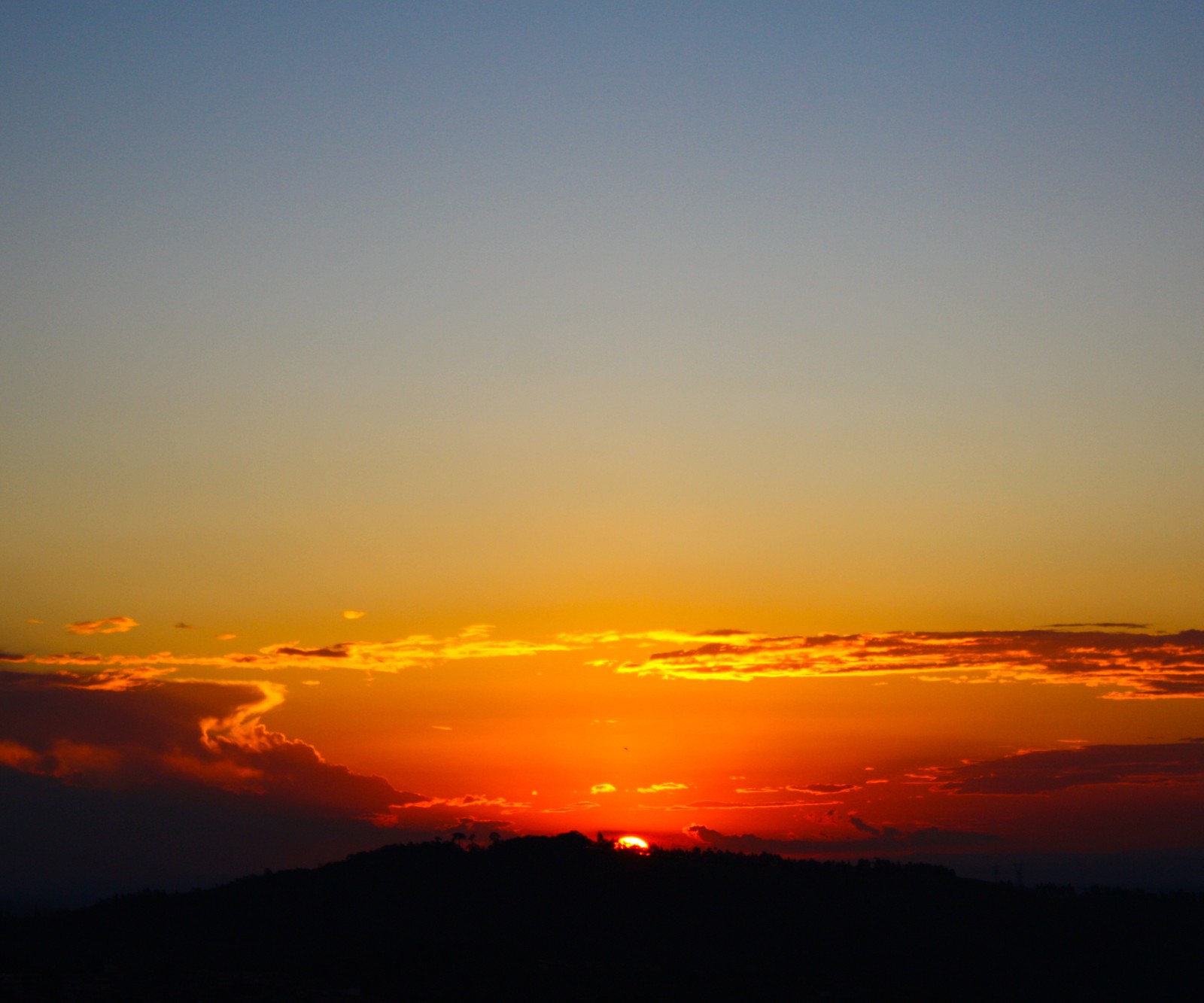 Uma girafa voando uma pipa no céu ao pôr do sol com uma montanha ao fundo (fim de tarde, nuvens, paisagem, por do sol, serranegra)