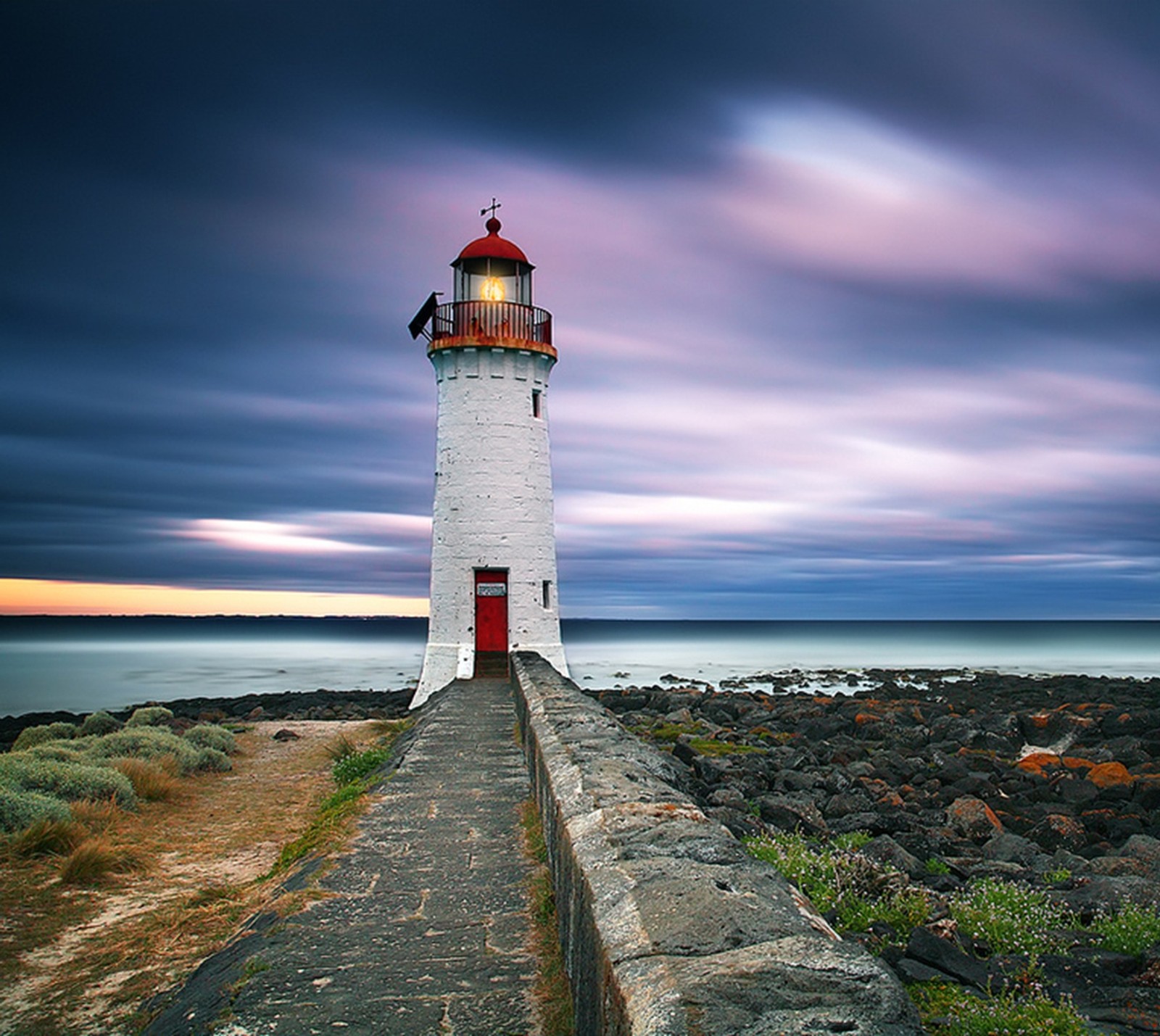 Arafed view of a lighthouse with a red door and a cloudy sky (amazing, clouds, house, light, nature)