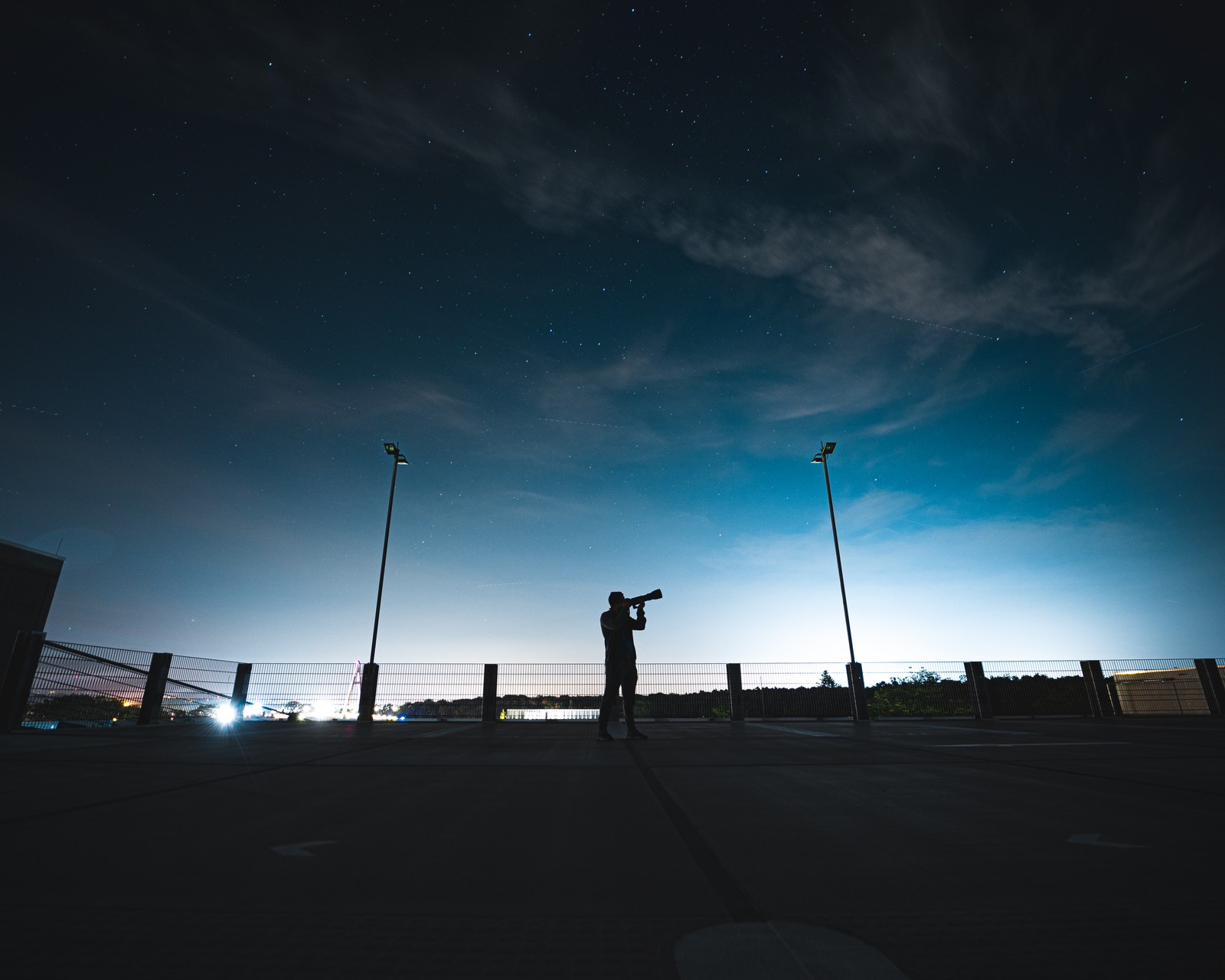 Un homme fait voler un cerf-volant dans le ciel (réverbère, nuage, nuit, lumière, atmosphère)