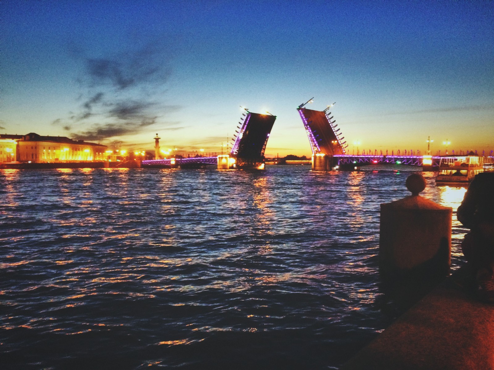 Pessoas sentadas em um cais assistindo a uma ponte abrir à noite (mar, horizonte, por do sol, água, anoitecer)