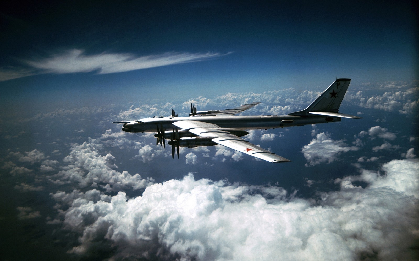 There is a large plane flying in the sky above the clouds (tupolev, aircraft, strategic bomber, military aircraft, airplane)