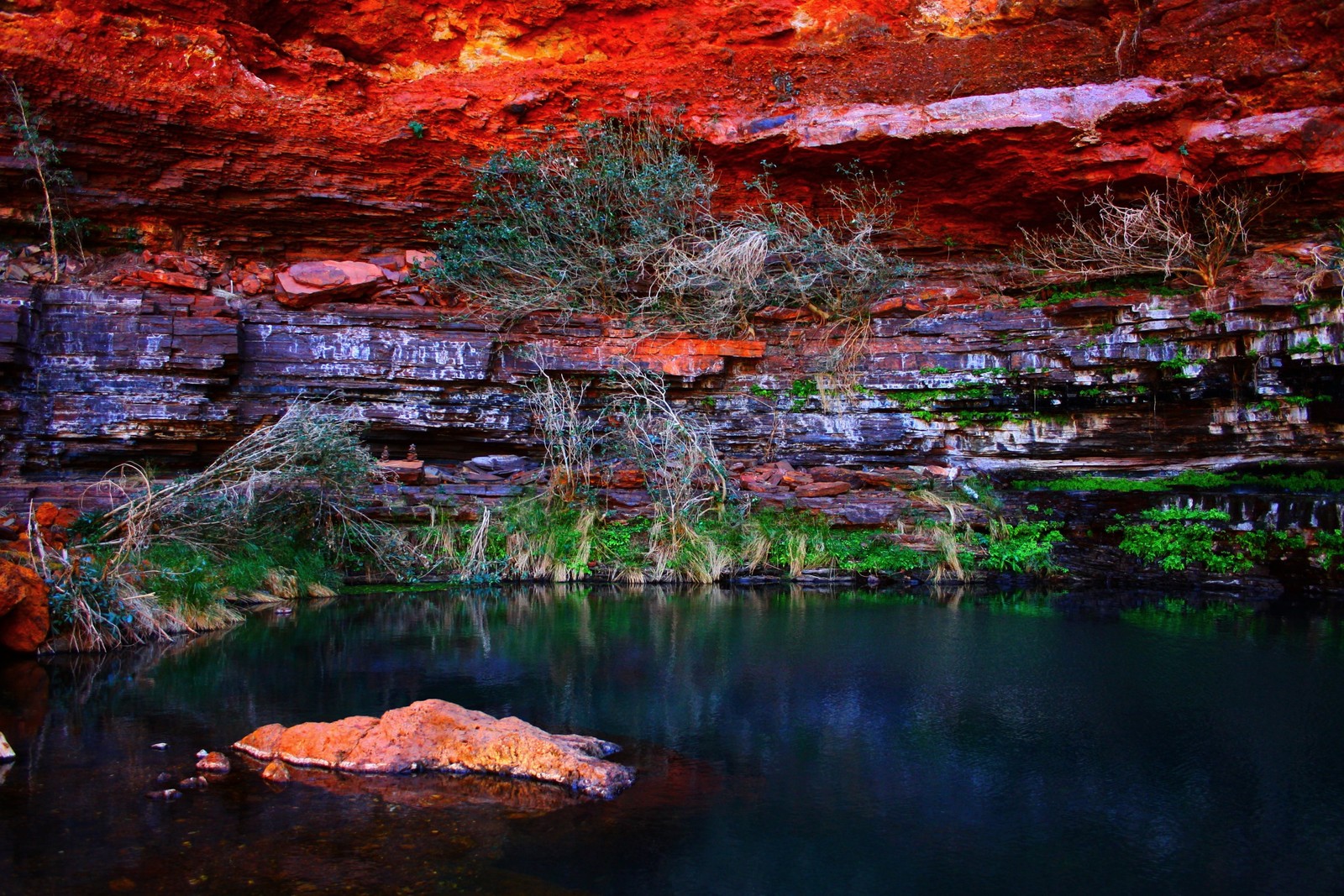 A close up of a rock in a body of water near a cliff (national park, park, nature, reflection, water)