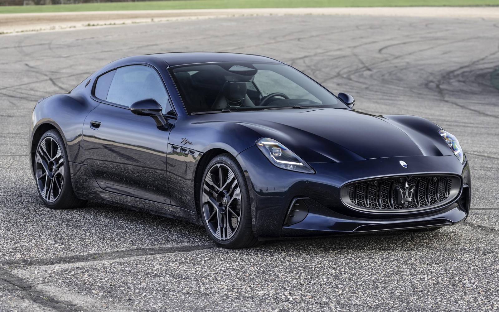 Um carro esportivo preto estacionado em uma pista com um campo verde ao fundo (maserati granturismo folgore, carros esportivos, 5k, 8k, carros)