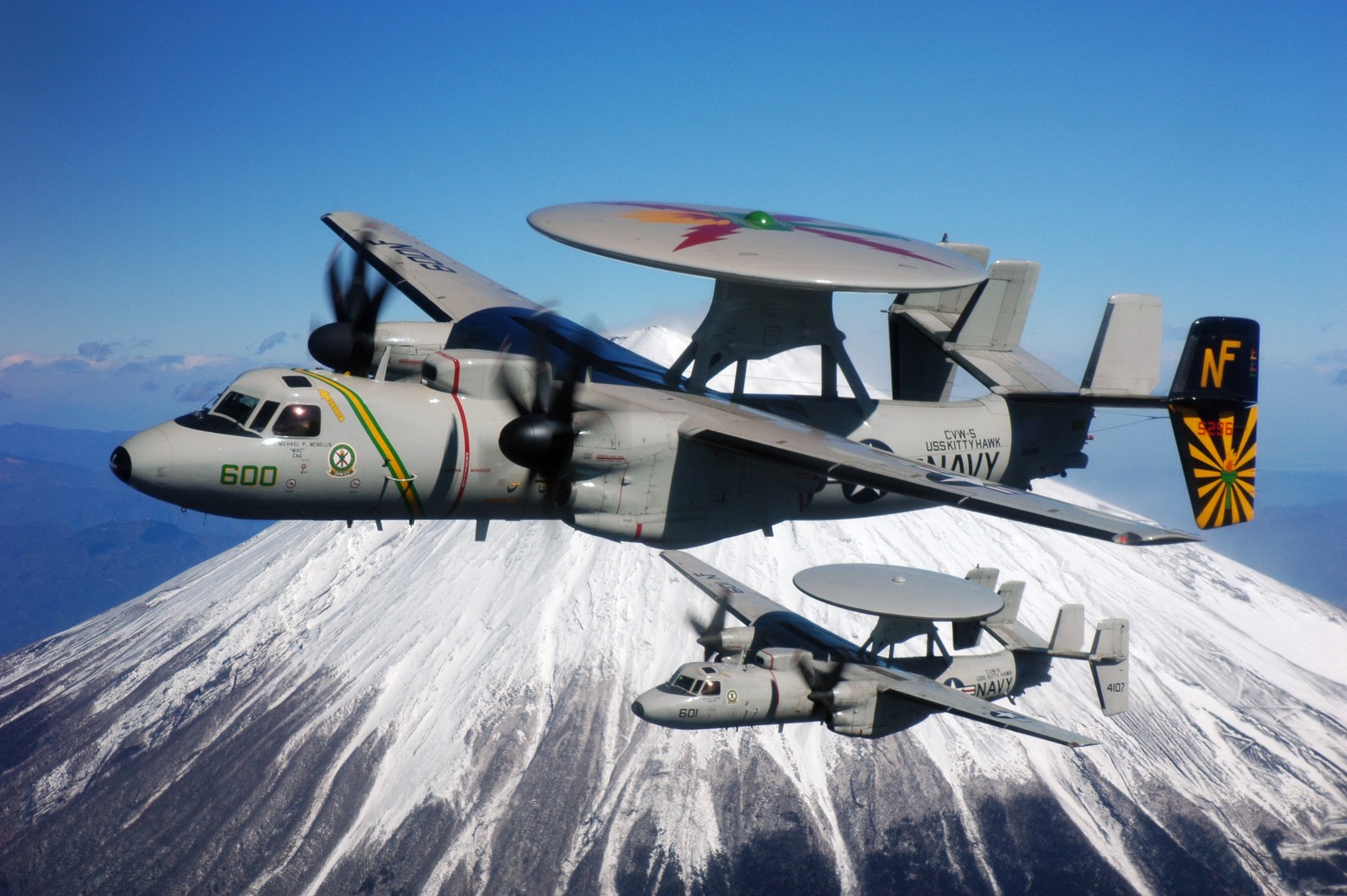 Ein kleines flugzeug fliegt über einen berg mit einer schneebedeckten spitze (flugzeug, marine der vereinigten staaten, militärflugzeug, grumman, propellerflugzeug)