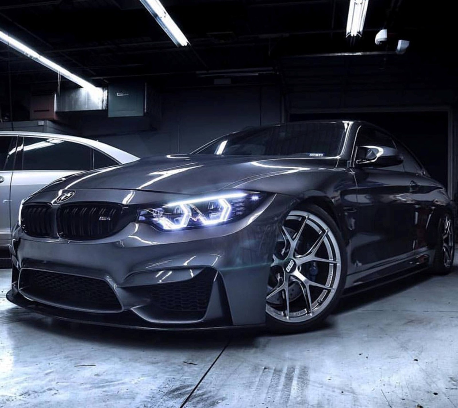 A close up of a car parked in a garage with other cars (bmw, car, garage, m4)