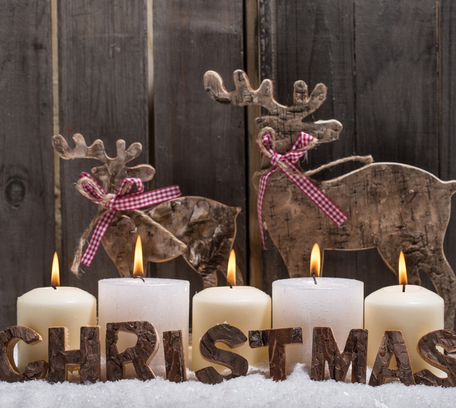 Candles are lit in front of a wooden sign with a reindeer and a reindeer (christmas, decoration, reindeers)