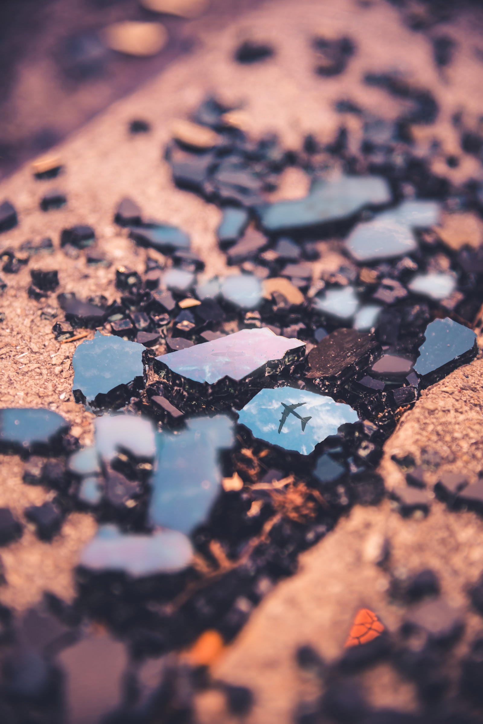 A close up of a broken glass on a sidewalk (apple, blue, water, soil, cloud)