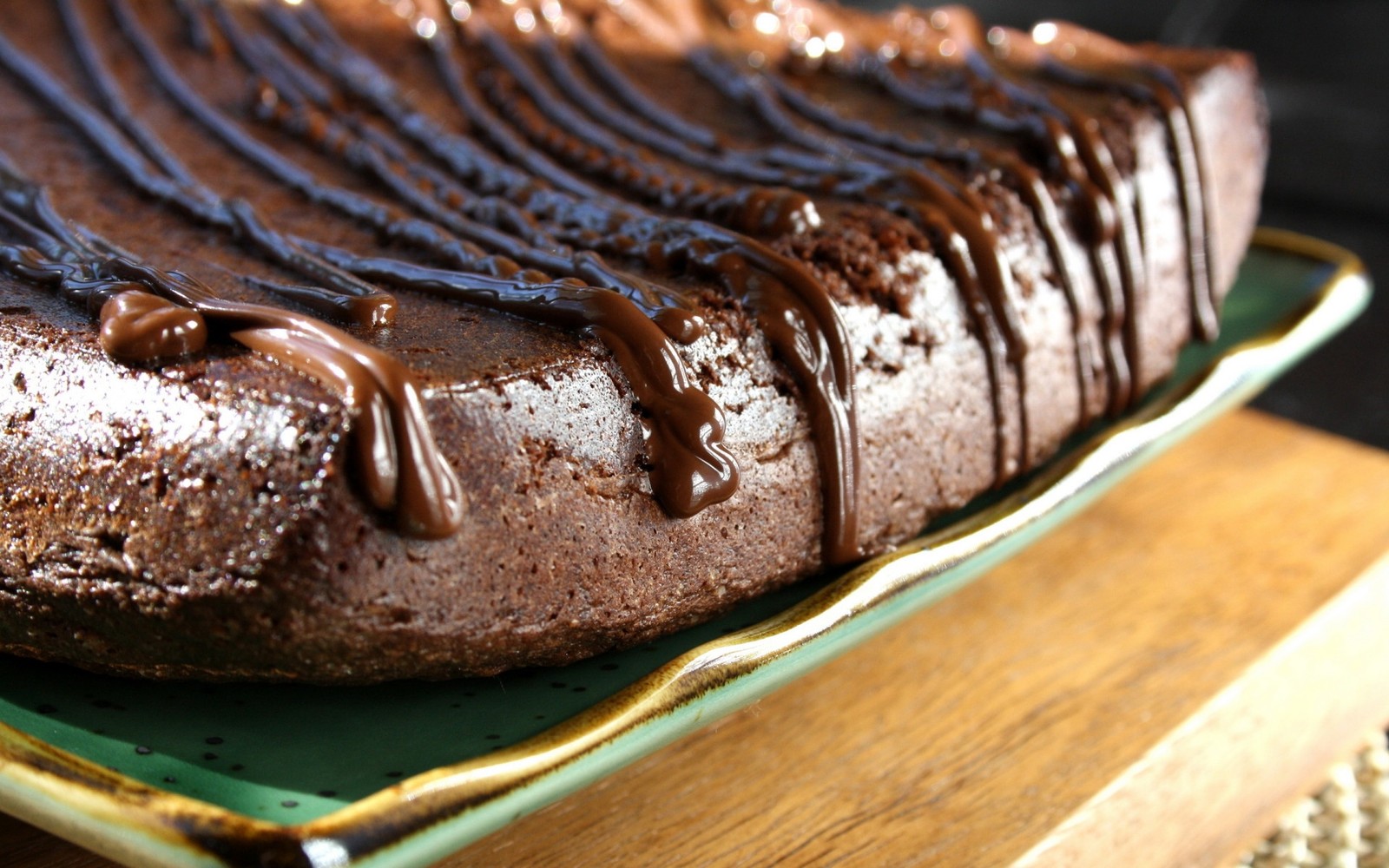 Es gibt einen schokoladenkuchen mit schokoladenglasur auf einem grünen teller (schokoladenkuchen, schokoladen brownie, fudge, backen, snackkuchen)