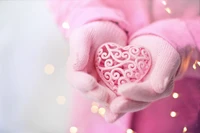 Delicate Pink Heart in Gloved Hands Against a Soft Background