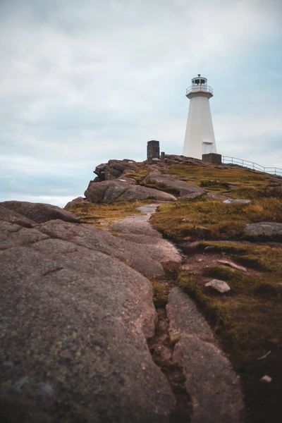 Phare sur la côte rocheuse sous un ciel nuageux