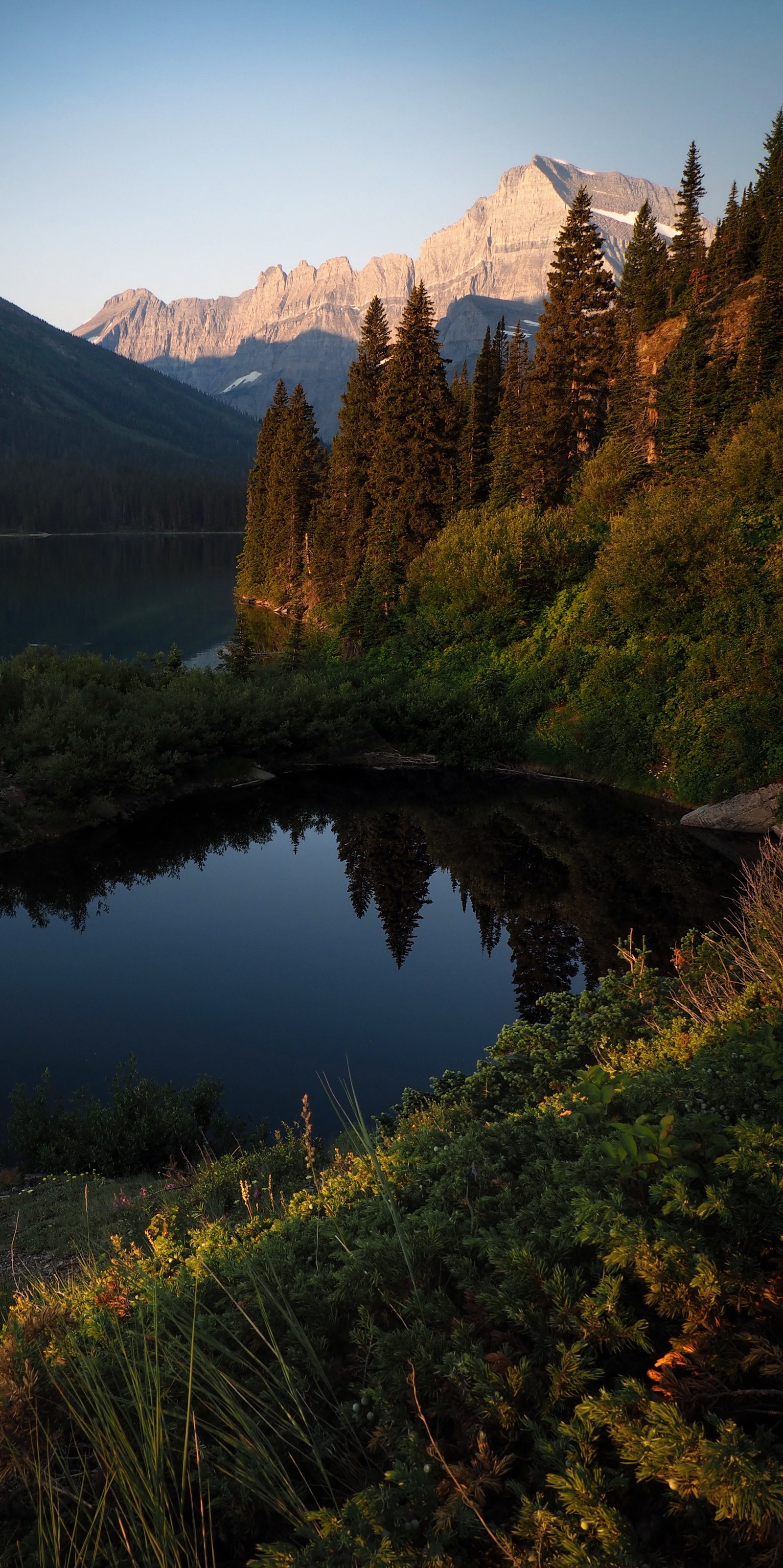 Montanhas ao fundo (texto religioso, two medicine lake, corpo de água, água, planta)