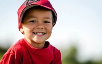 Joyful child in a baseball cap, radiating laughter and vibrant emotion.